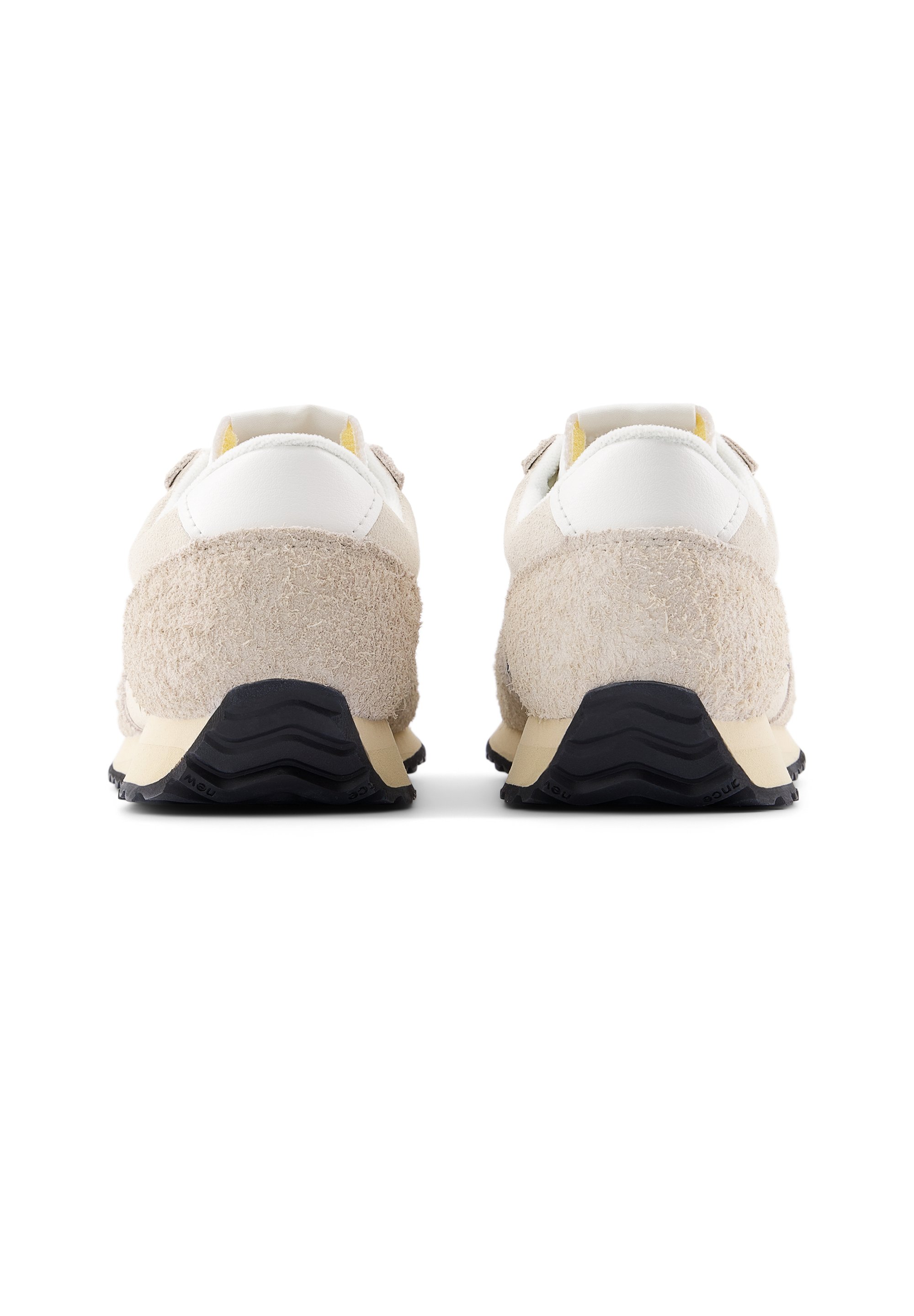 Zapatillas de color crema con una parte trasera de ante beige texturizado, detalles en cuero blanco y una suela de goma negra con un patrón en zigzag.