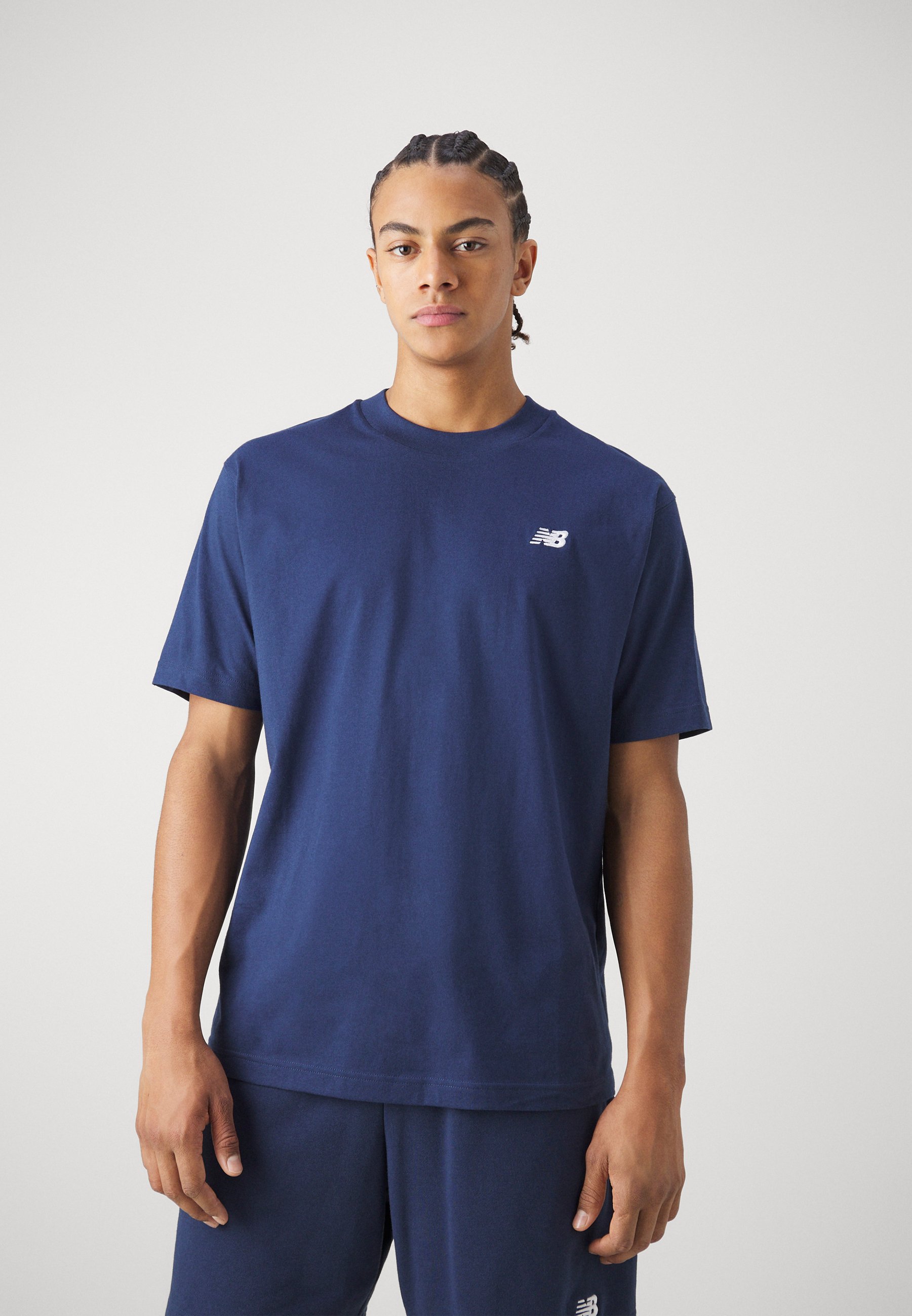 Camiseta de algodón azul marino con cuello redondo y mangas cortas, con un pequeño logo blanco en la parte izquierda del pecho. Diseño sencillo.
