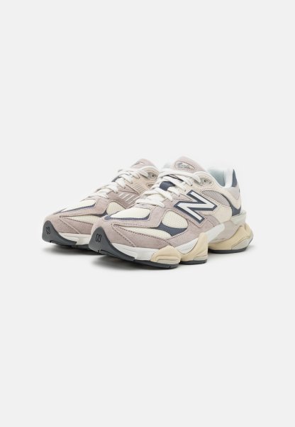 Zapatillas de running en beige y crema con materiales de malla y ante, que presentan un acento en azul oscuro, puntera redonda y suela gruesa y texturizada.