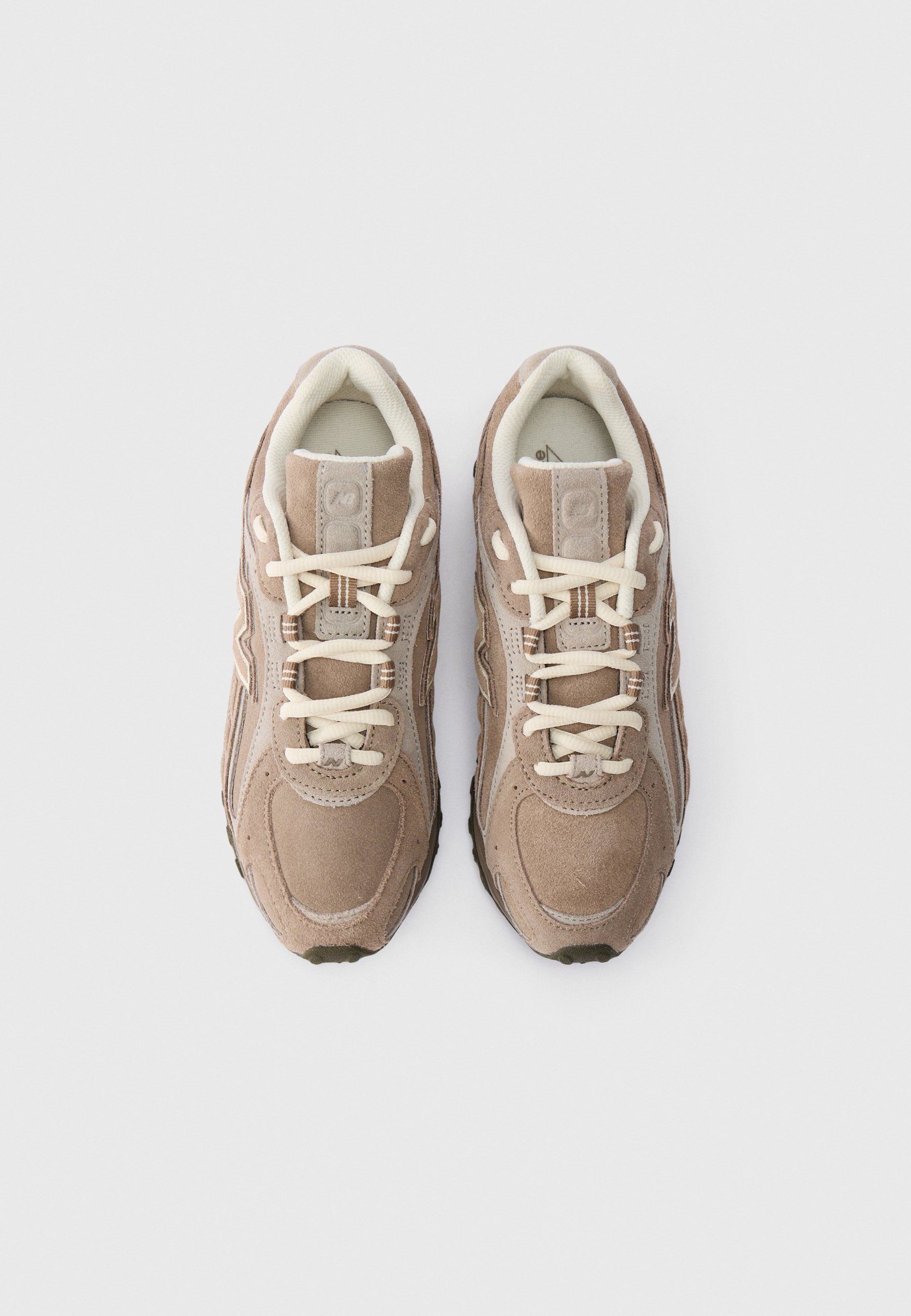 Par de zapatillas de ante beige con cordones crema, vistas desde arriba sobre un fondo blanco.