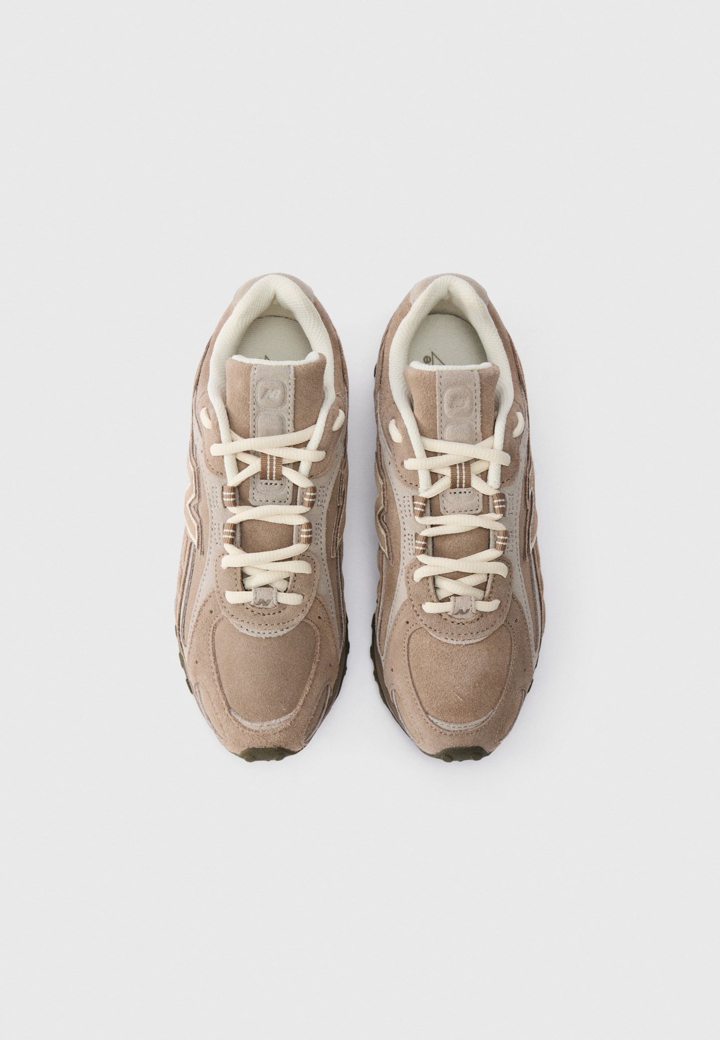 Par de zapatillas de ante beige con cordones crema, vistas desde arriba sobre un fondo blanco.