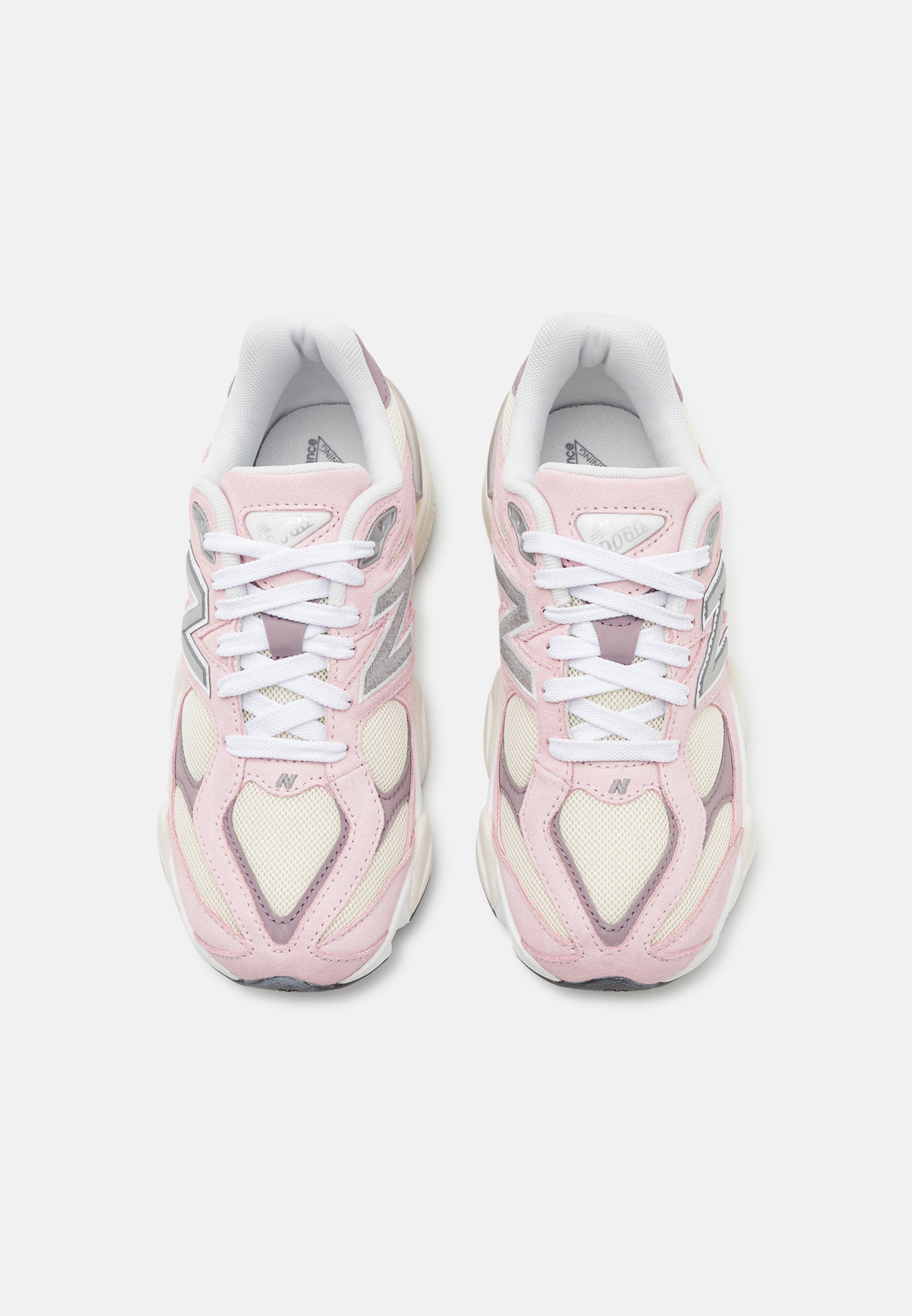 Zapatillas de color rosa claro con acentos en blanco y gris. Los materiales de malla y ante forman la parte superior. Cuenta con cordones blancos y un cuello acolchado.