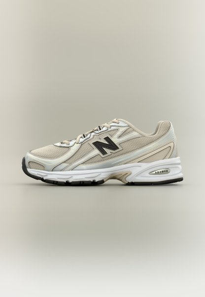 Zapatilla deportiva New Balance beige y blanca con paneles de malla, logo negro en el lateral y suela blanca acolchada con etiqueta de tecnología ABSORB.