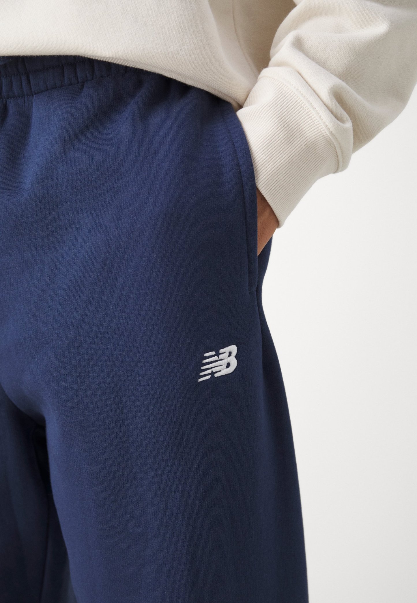 Pantalones de chándal azul marino hechos de una tela suave, con un logotipo bordado en blanco en el muslo y una cinturilla elástica con bolsillos.