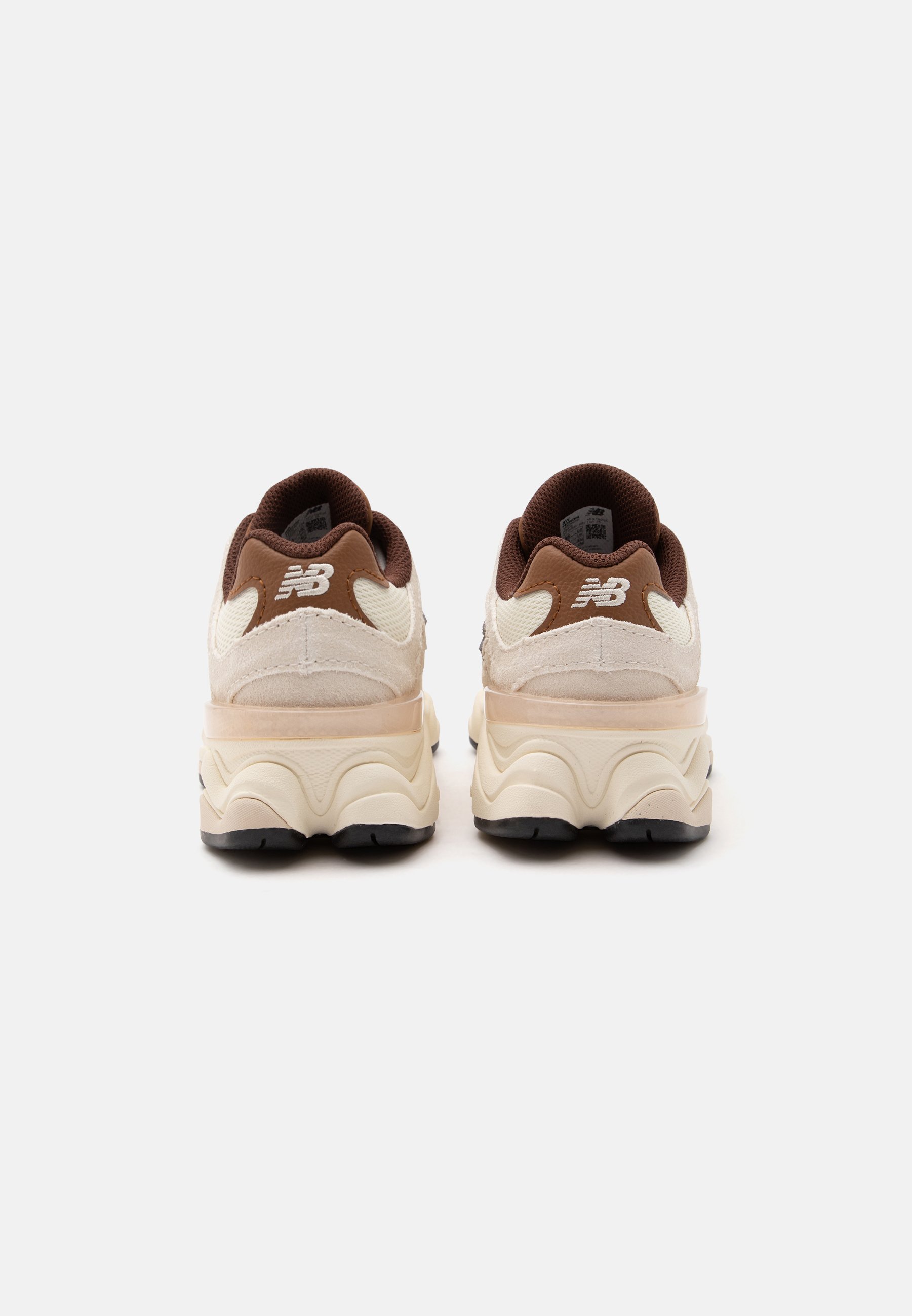 Par de zapatillas New Balance beige y marrones vistas desde atrás con suelas gruesas y curvadas y logo en la lengüeta del talón.