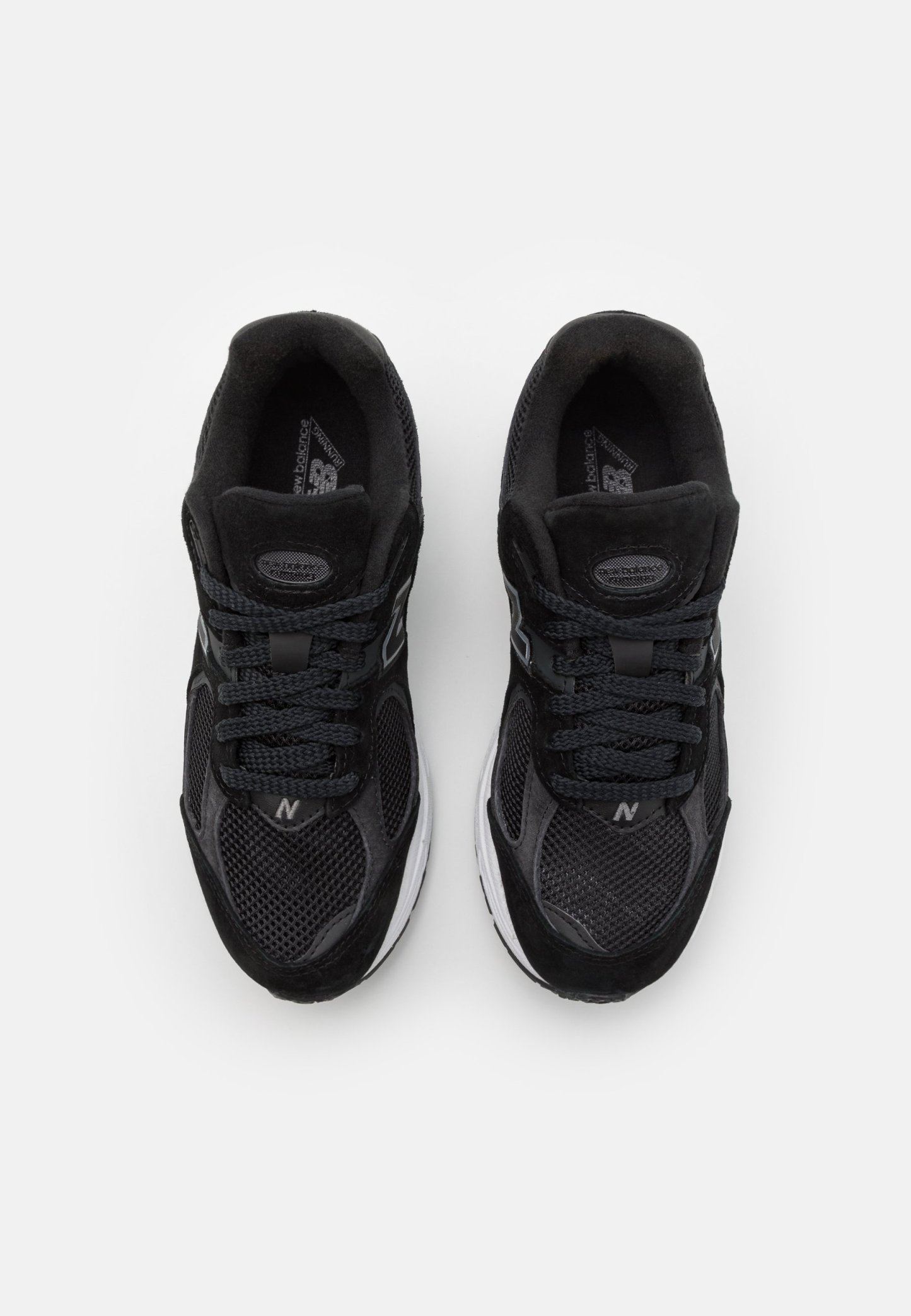 Zapatillas deportivas negras con materiales de malla y ante, que cuentan con una suela acolchada, cordones redondos y un logo en el lateral.