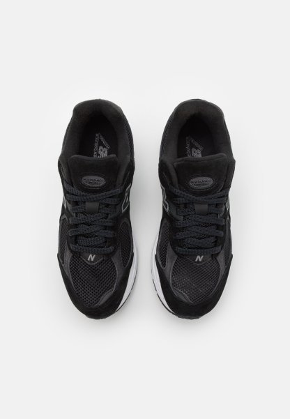 Zapatillas deportivas negras con materiales de malla y ante, que cuentan con una suela acolchada, cordones redondos y un logo en el lateral.
