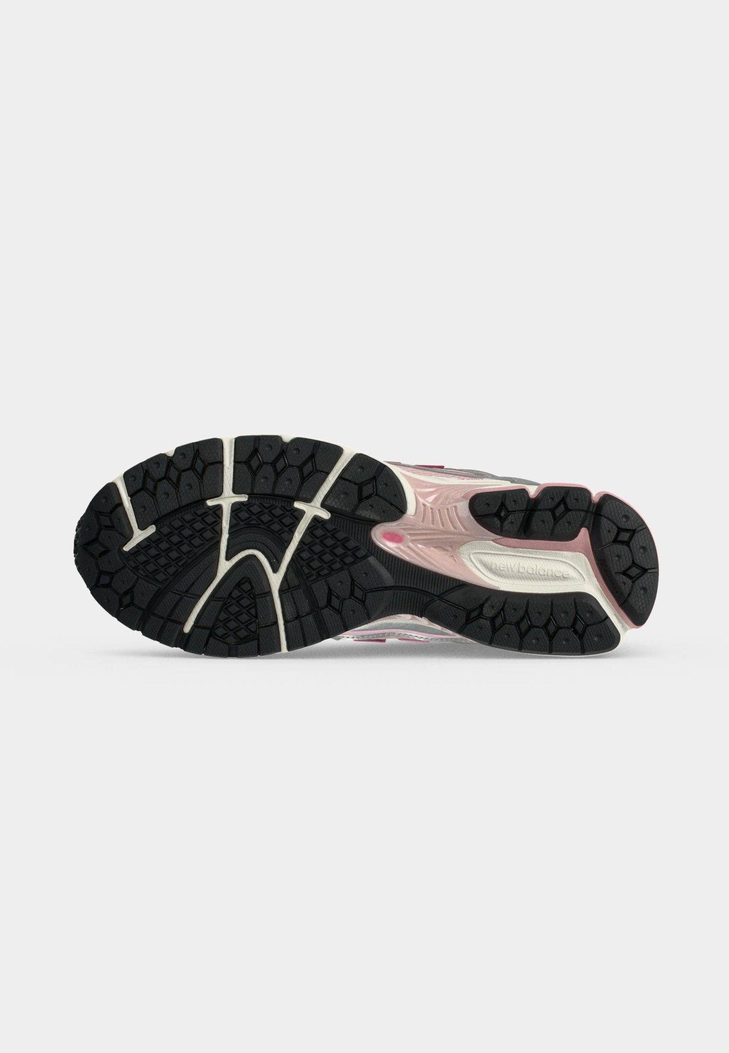 Suela de zapato con patrón de banda de rodadura en blanco y negro, detalle rosa en la entresuela y logotipo de New Balance sobre un fondo liso gris claro.
