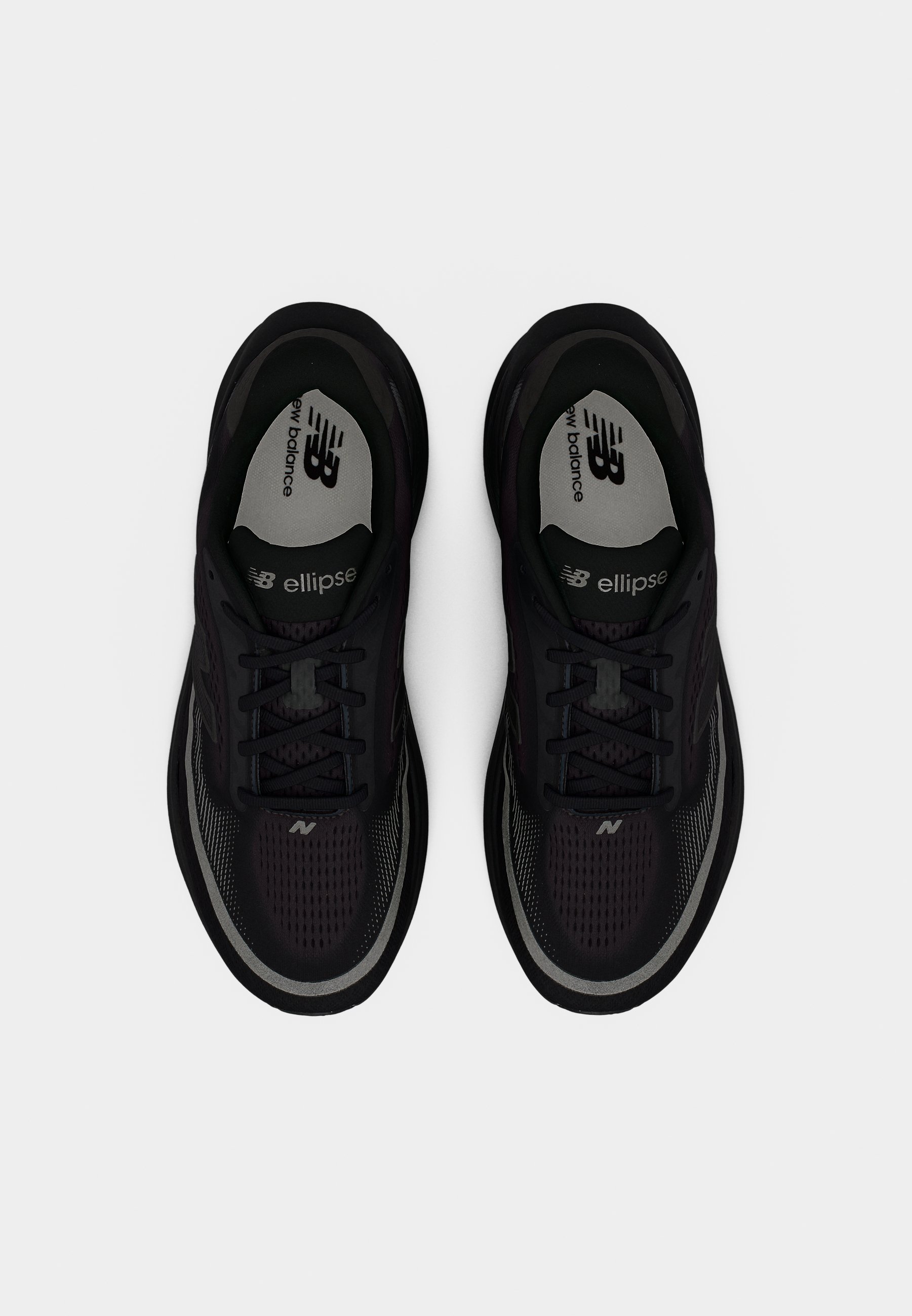 Zapatillas deportivas negras con parte superior de malla, diseño con cordones y suela de goma. Presentan detalles en gris y la marca "New Balance" en la plantilla.