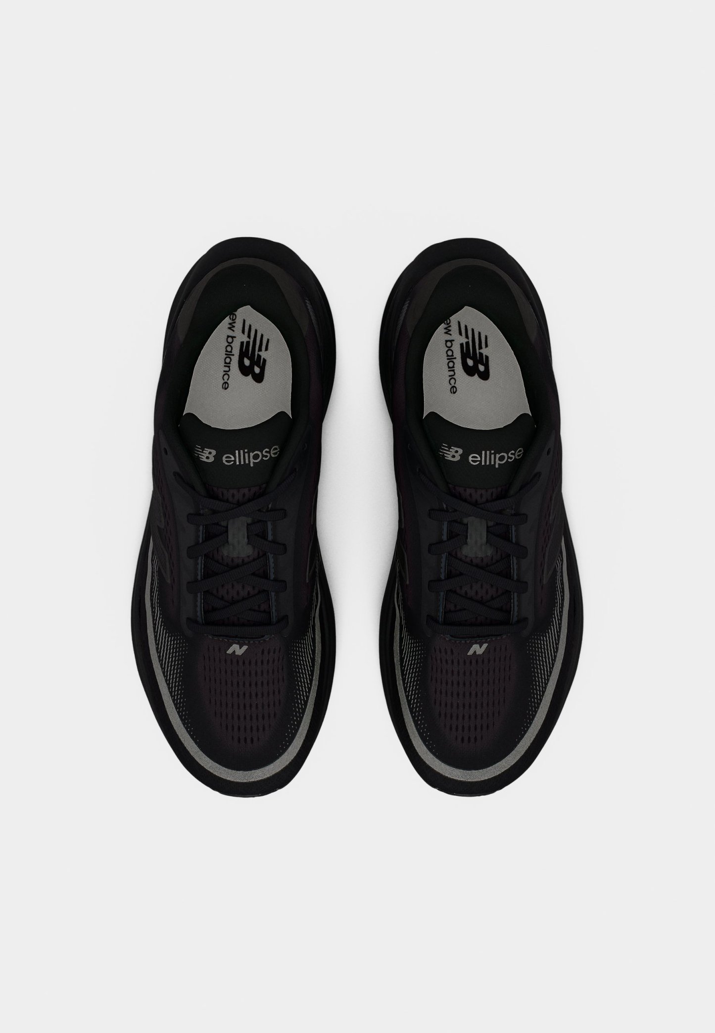 Zapatillas deportivas negras con parte superior de malla, diseño con cordones y suela de goma. Presentan detalles en gris y la marca "New Balance" en la plantilla.