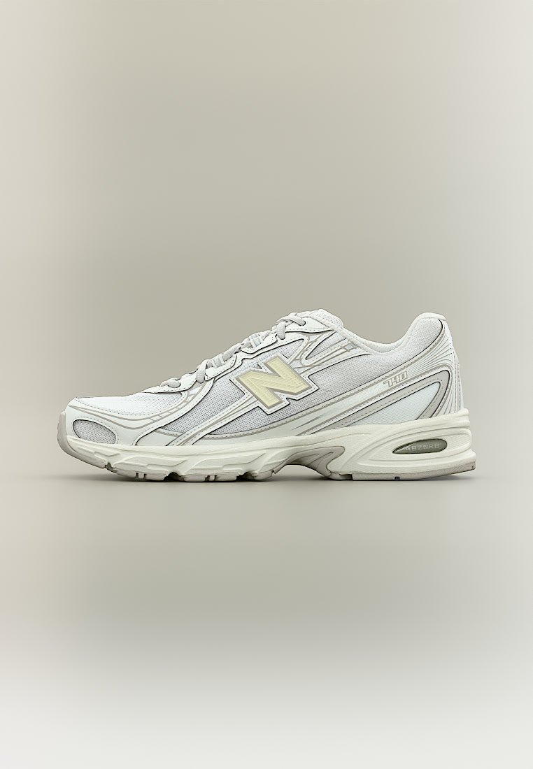 Zapatilla de running New Balance 740 blanca con parte superior de malla y sintética, suela acolchada y diseño con cordones sobre fondo gris neutro.