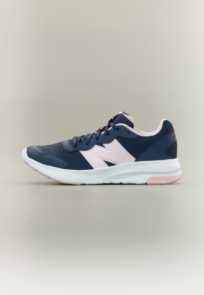 Zapatilla de correr New Balance azul marino y rosa claro con suela blanca, vista lateral sobre fondo claro y liso.