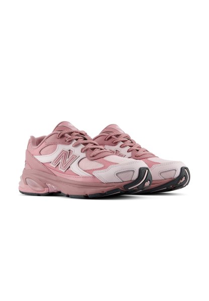 Par de zapatillas deportivas New Balance rosas y blancas con cordones sobre un fondo blanco, inclinadas para mostrar detalles laterales y frontales.