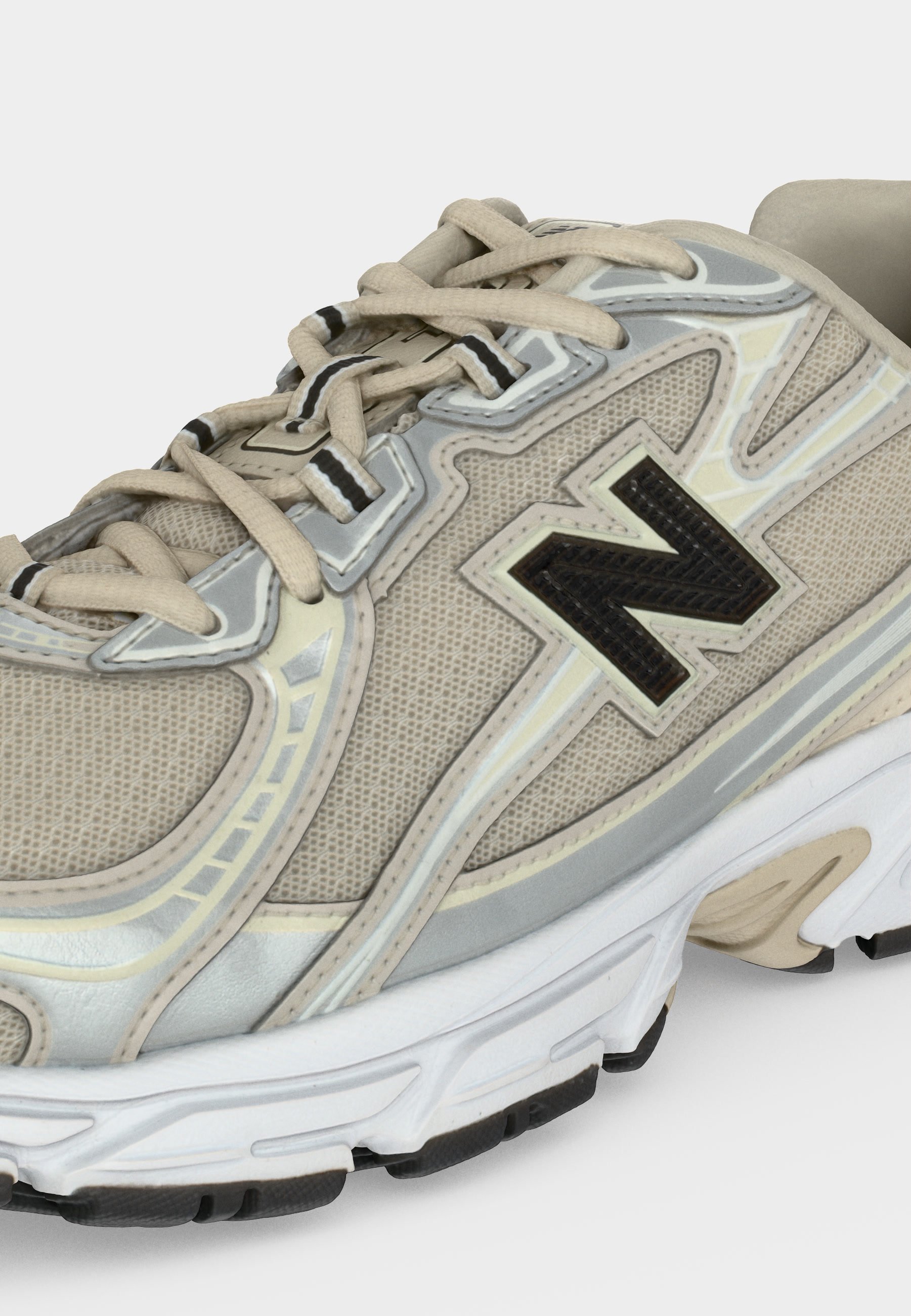 Zapatilla de running en beige y gris con logo "N" negro, cordones beige claro y suela blanca con detalles negros en la banda de rodadura.