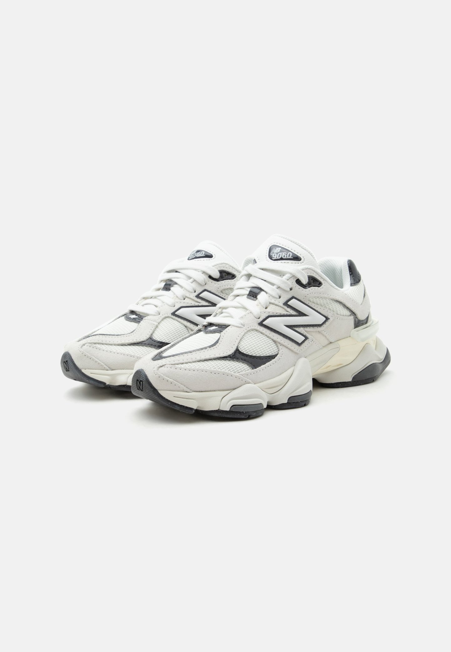 Zapatillas New Balance 9060 blancas y grises con paneles de malla y cuero, suelas gruesas y logo "N" en los laterales y las lengüetas.
