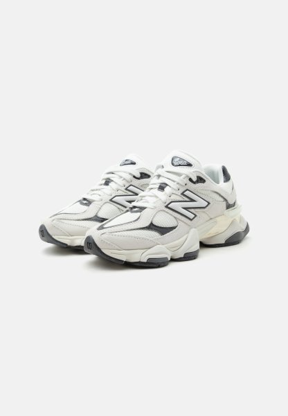 Zapatillas New Balance 9060 blancas y grises con paneles de malla y cuero, suelas gruesas y logo "N" en los laterales y las lengüetas.