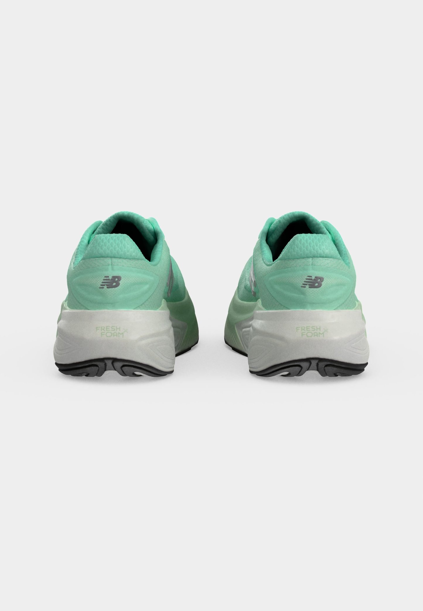 Par de zapatillas de running New Balance en verde menta vistas desde atrás, mostrando suelas blancas con dibujo negro y la marca Fresh Foam.