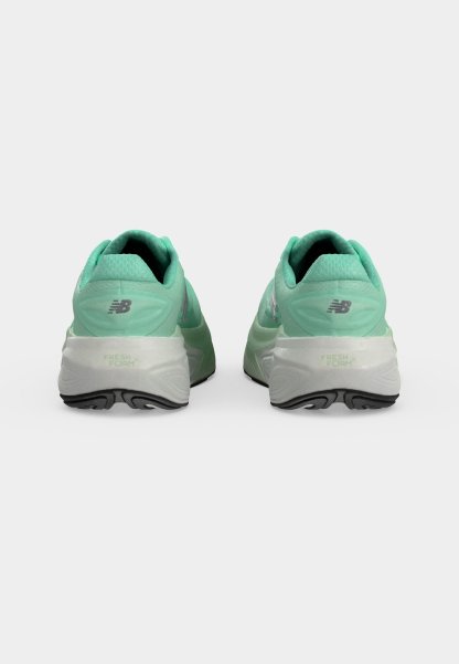Par de zapatillas de running New Balance en verde menta vistas desde atrás, mostrando suelas blancas con dibujo negro y la marca Fresh Foam.