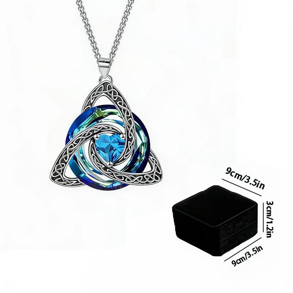 Silver Celtic knot triquetra pendant necklace with a blue faceted crystal center, shown on a white background with a small inset of the black square glass mold used to cast the pendant.