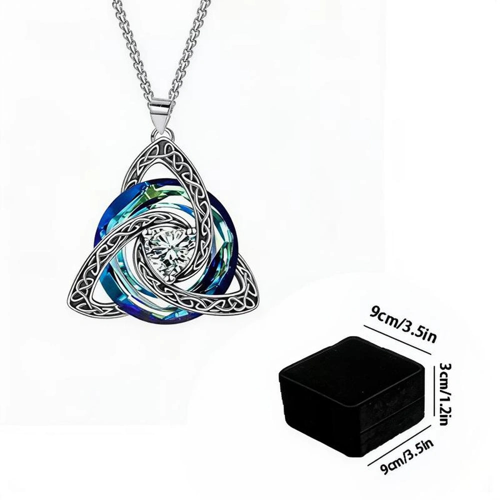 Silver Celtic knot triquetra pendant necklace with a blue and green iridescent circular center and a clear crystal, shown on a white background with a black square box and dimension labels.