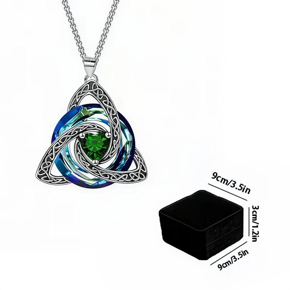 Silver Celtic knot triquetra pendant necklace with a blue and white spiral design and a green crystal center, shown alongside a black storage box and dimension labels.