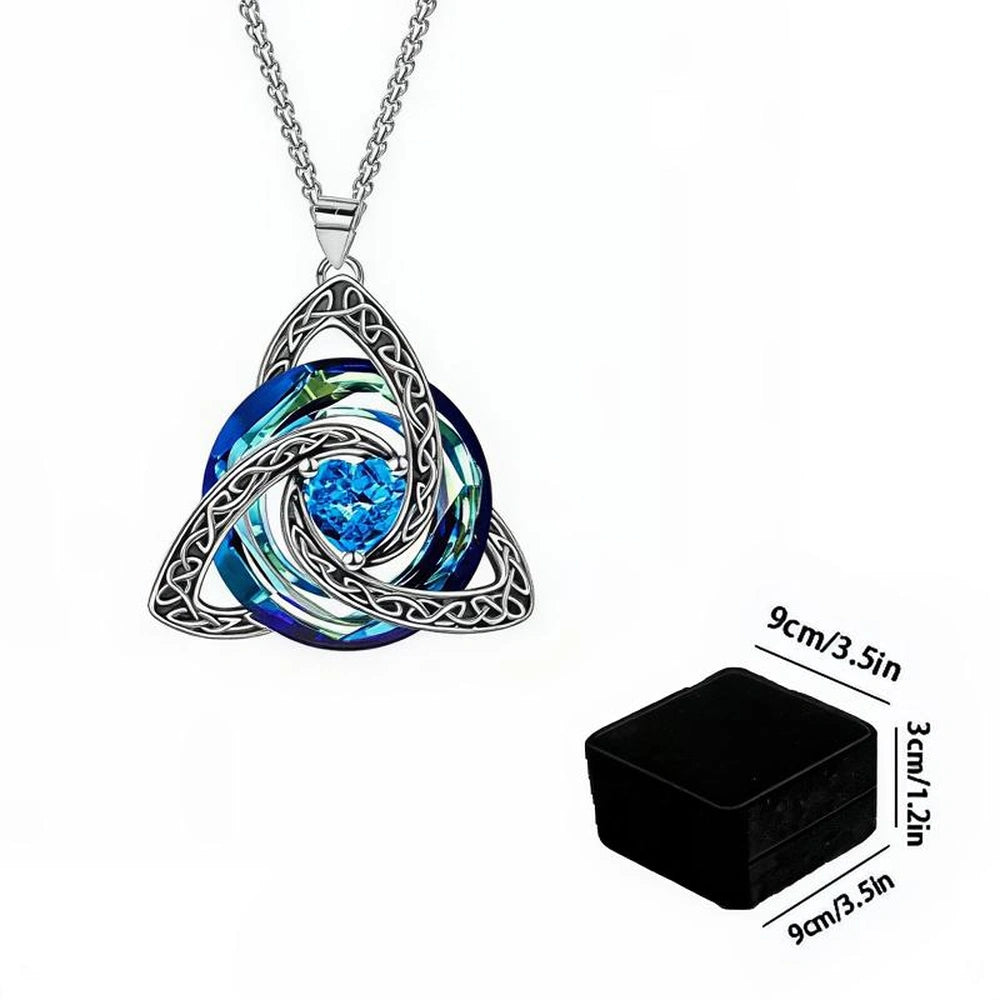 Silver-toned Celtic knot triquetra pendant necklace with a blue iridescent swirl design and a central blue gemstone, shown on a white background with a small inset of the black square jewelry box dimensions.