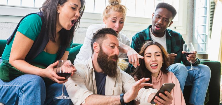 people laughing and sharing a social media post with friends