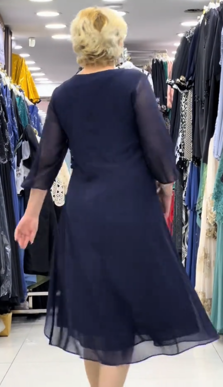 Prosta sukienka z okrągłym dekoltem, rękawami do kolan i wyjątkowymi zdobieniami z cekinów na ramionach.