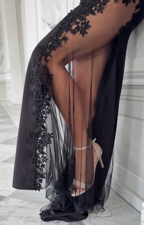 Sukienka na ramiączkach typu spaghetti z głębokim dekoltem w serek i wysokim rozcięciem, wykonana z półprzezroczystego materiału i ozdobiona aplikacjami.