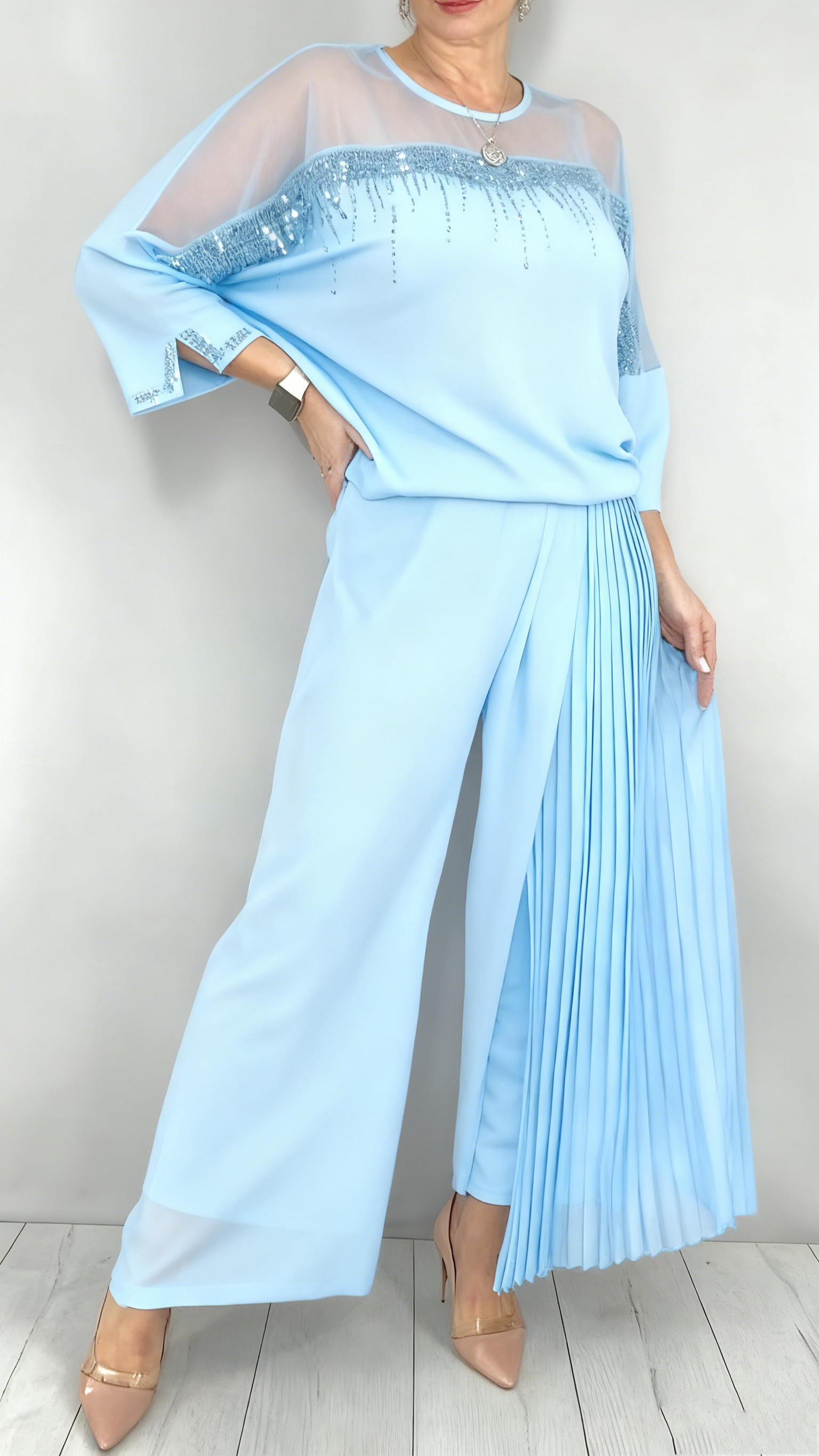 Garnitur z przezroczystym tiulem i cekinami na rękawach i dekolcie oraz plisowanymi panelami na spodniach.