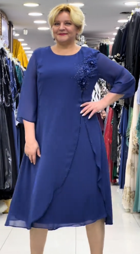 Prosta sukienka z okrągłym dekoltem, rękawami do kolan i wyjątkowymi zdobieniami z cekinów na ramionach.