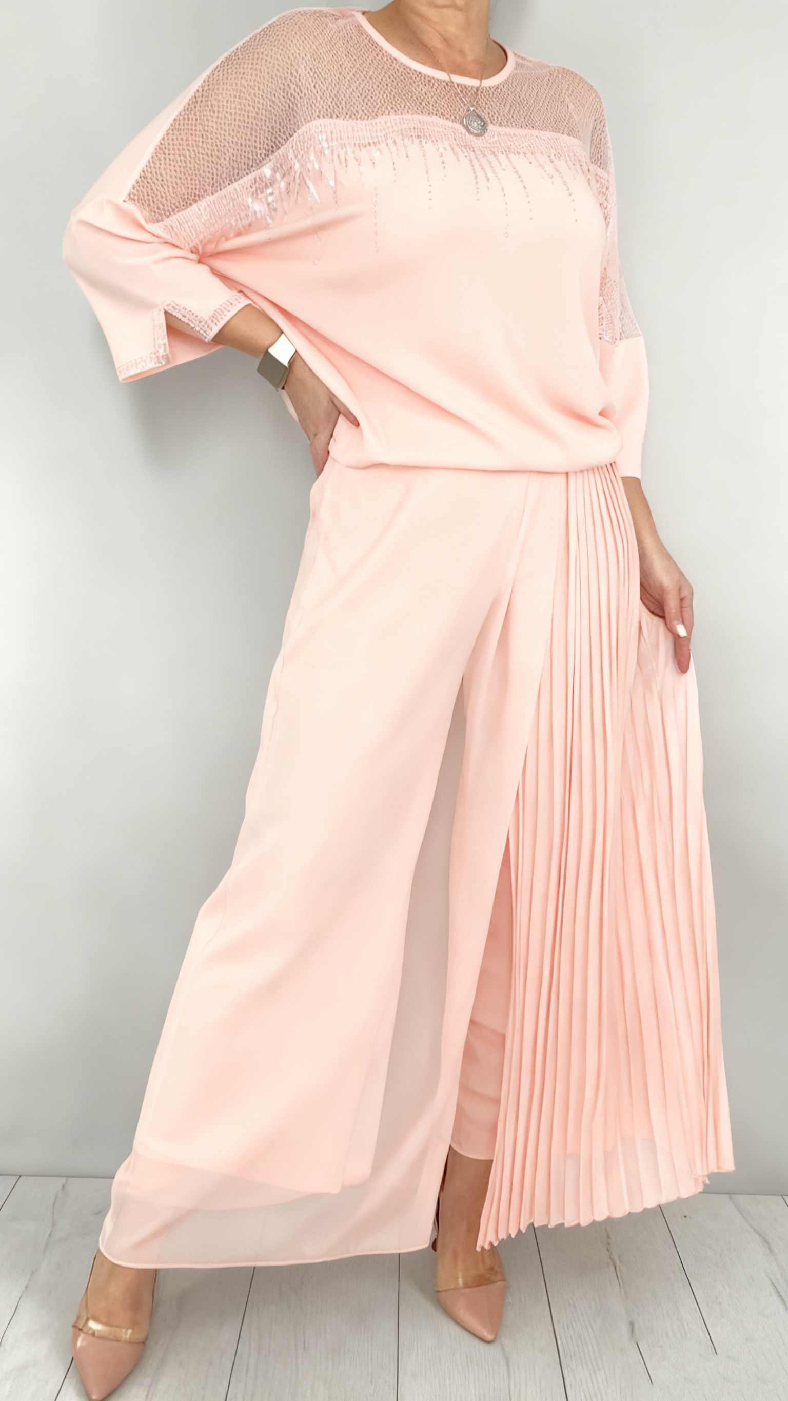 Garnitur z przezroczystym tiulem i cekinami na rękawach i dekolcie oraz plisowanymi panelami na spodniach.