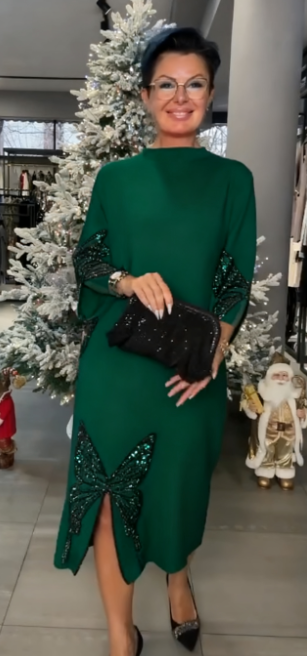 Ta sukienka ozdobiona jest cekinowym wzorem przedstawiającym motyle, ma rozcięcie i wysoki dekolt.