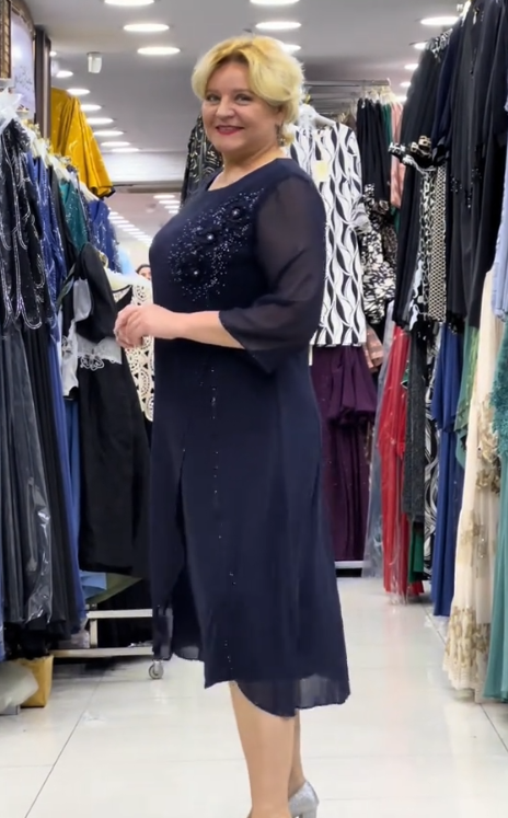 Prosta sukienka z okrągłym dekoltem, rękawami do kolan i wyjątkowymi zdobieniami z cekinów na ramionach.