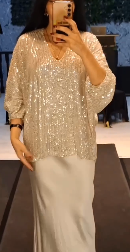 Strój składający się z koszuli z cekinami i długiej, zwiewnej, eleganckiej spódnicy.