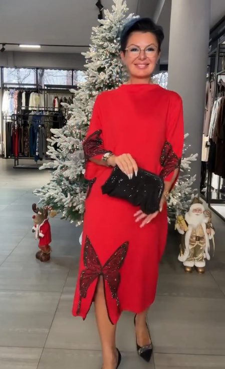 Ta sukienka ozdobiona jest cekinowym wzorem przedstawiającym motyle, ma rozcięcie i wysoki dekolt.