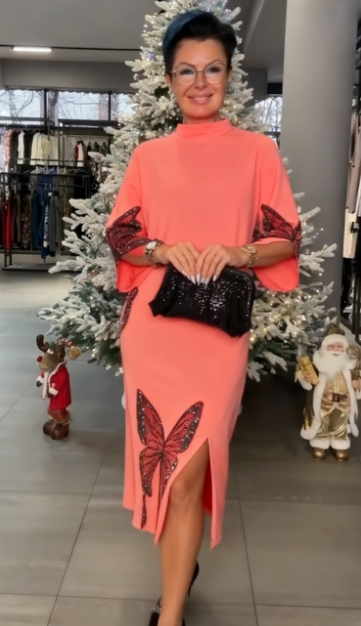 Ta sukienka ozdobiona jest cekinowym wzorem przedstawiającym motyle, ma rozcięcie i wysoki dekolt.