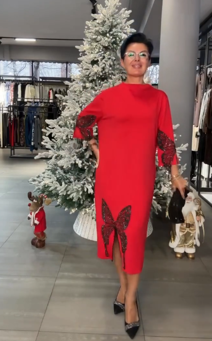 Ta sukienka ozdobiona jest cekinowym wzorem przedstawiającym motyle, ma rozcięcie i wysoki dekolt.