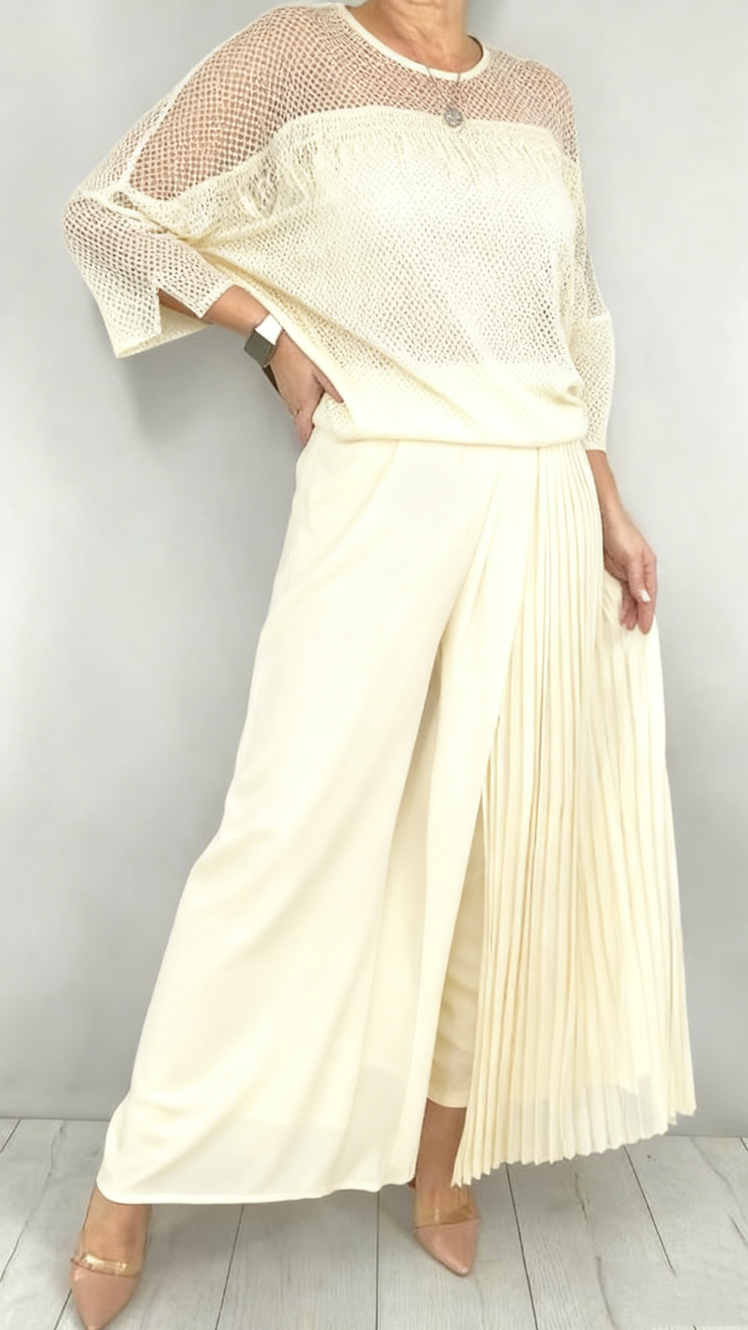 Garnitur z przezroczystym tiulem i cekinami na rękawach i dekolcie oraz plisowanymi panelami na spodniach.