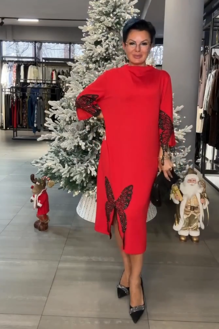 Ta sukienka ozdobiona jest cekinowym wzorem przedstawiającym motyle, ma rozcięcie i wysoki dekolt.