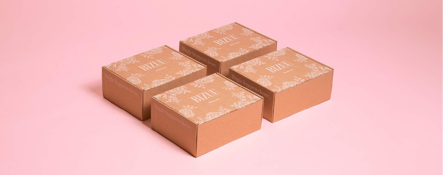 Kartony Bizuu ułożone na r&oacute;żowym tle