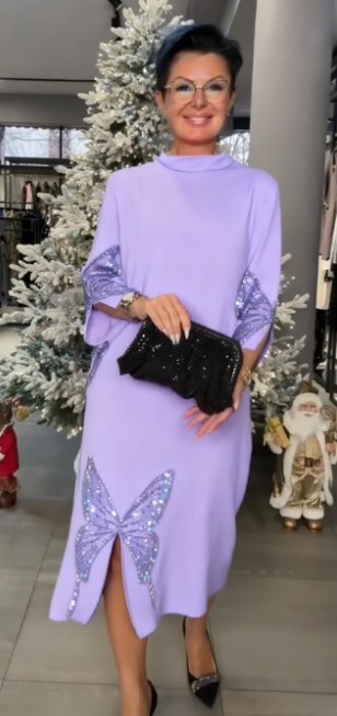 Ta sukienka ozdobiona jest cekinowym wzorem przedstawiającym motyle, ma rozcięcie i wysoki dekolt.