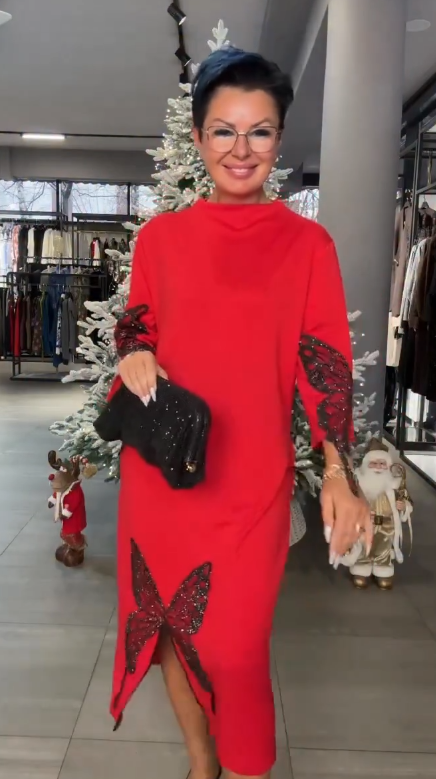 Ta sukienka ozdobiona jest cekinowym wzorem przedstawiającym motyle, ma rozcięcie i wysoki dekolt.