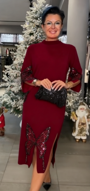 Ta sukienka ozdobiona jest cekinowym wzorem przedstawiającym motyle, ma rozcięcie i wysoki dekolt.