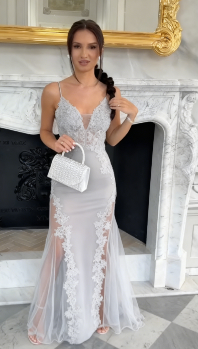 Sukienka na ramiączkach typu spaghetti z głębokim dekoltem w serek i wysokim rozcięciem, wykonana z półprzezroczystego materiału i ozdobiona aplikacjami.