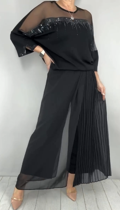 Garnitur z przezroczystym tiulem i cekinami na rękawach i dekolcie oraz plisowanymi panelami na spodniach.