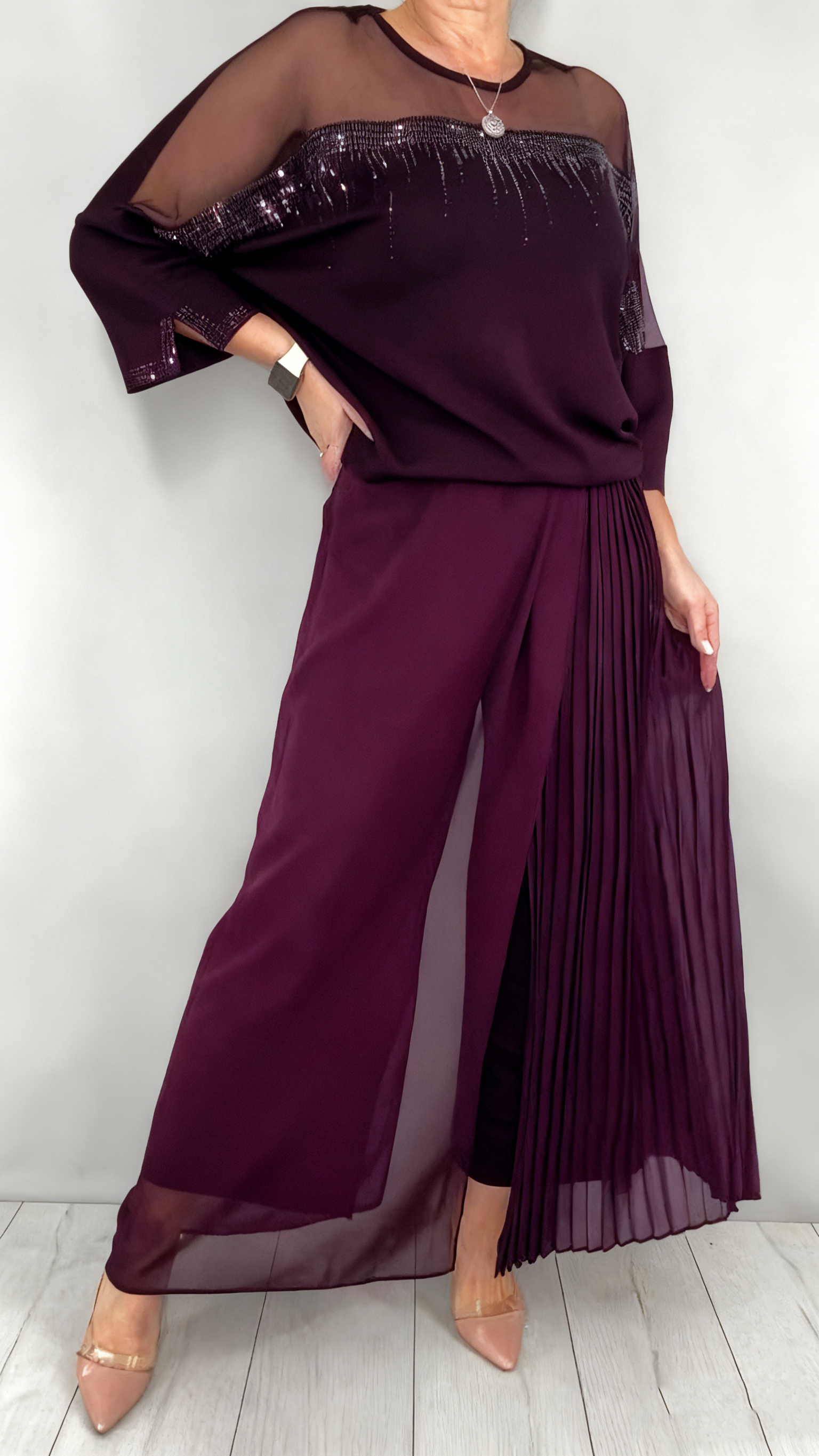 Garnitur z przezroczystym tiulem i cekinami na rękawach i dekolcie oraz plisowanymi panelami na spodniach.