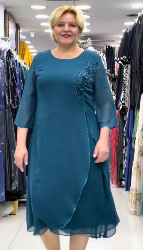 Prosta sukienka z okrągłym dekoltem, rękawami do kolan i wyjątkowymi zdobieniami z cekinów na ramionach.