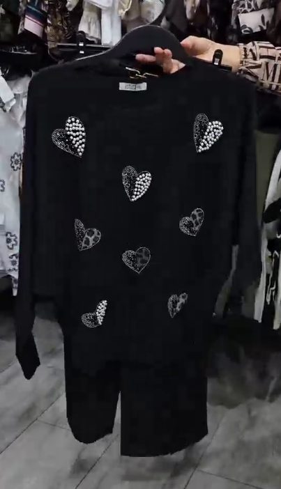 Marynarka ozdobiona wzorem w serca, zestawiona z czarnymi spodniami.