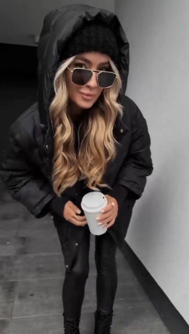 Kurtka puchowa z kapturem i fakturowaną fakturą, sięgająca do połowy łydki.